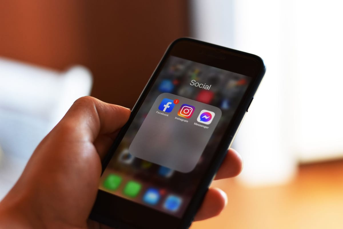 main tenant un smartphone ouvert sur les applications de réseaux sociaux